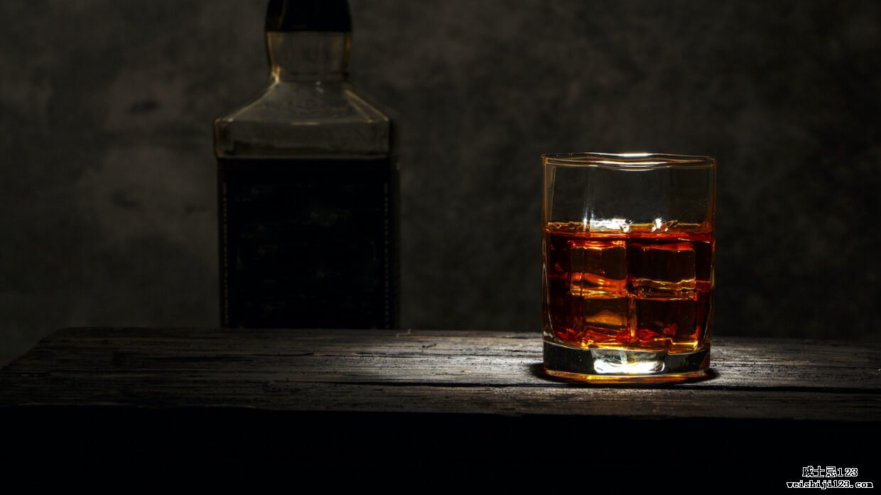 聚光灯下的一杯威士忌，背后的阴影中有一个身份不明的瓶子